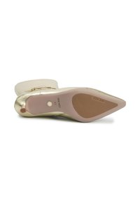 Zlaté boty na podpatku s špičatou špičkou. Hladký svršek a texturovaná růžová gumová podešev, na které je uvedeno jméno značky "NINE WEST" a velikost "37."