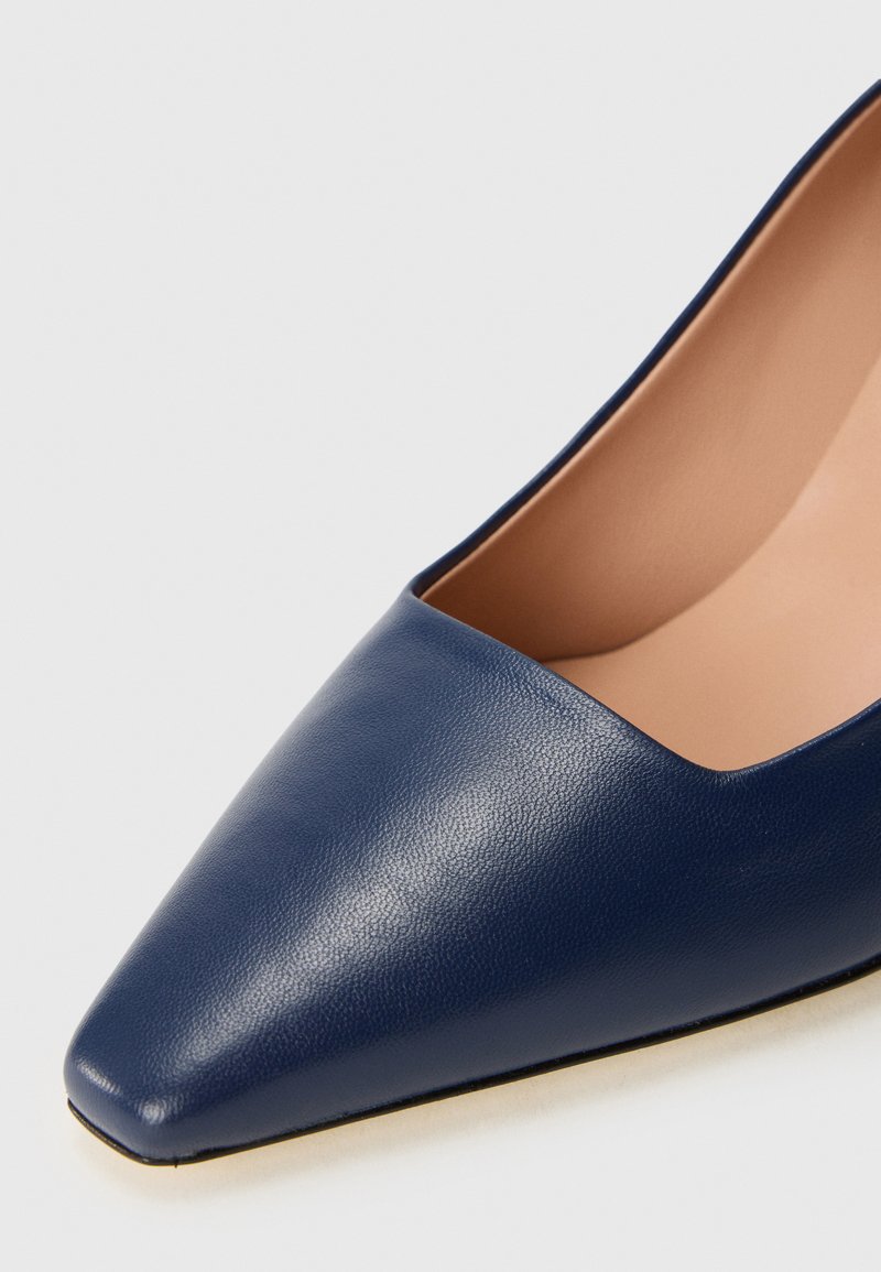 Scarpa in pelle blu navy con punta affusolata e superficie liscia, dotata di una fodera interna color nude e una scollatura bassa sui lati per un aspetto elegante.