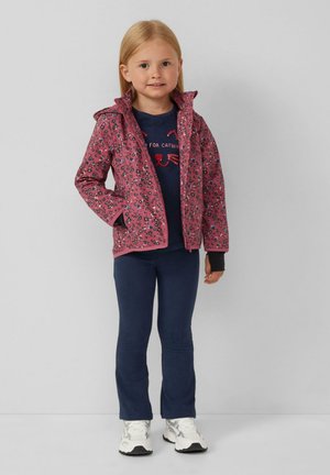 Pinker Jacke mit Blumenmuster und Kapuze über einem marineblauen Shirt mit einem Katzendesign, kombiniert mit marineblauen Leggings und weißen Sneakers.