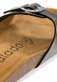 Svart texturerad slide-sandal med en silverfärgad spänne, som har en mjuk tan-suede innersula och en ljusbrun korkfotbädd.