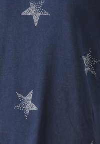 Tejido azul marino con una textura suave que presenta patrones de estrellas blancas adornadas con pequeños puntos dispuestos en varios tamaños.