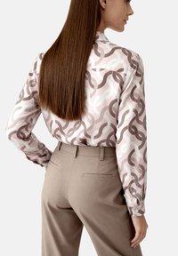 Long-sleeve shirt in light pink with wavy brown and white patterns. Pair with beige trousers featuring back pockets and tailored design.