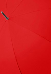 Close-up van de bovenkant in het midden van een rode parasol met zichtbare ribben en de punt van de steel van de parasol.