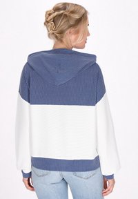 Felpa con cappuccio dallo stile a blocchi di colore blu e bianco. Tessuto testurizzato, con strisce blu e polsini elastici con finitura a coste.