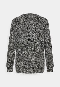 Blusa preta de manga longa com um padrão texturizado de manchas brancas. Gola redonda simples, tecido suave e punhos franzidos nas extremidades das mangas.