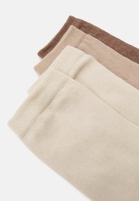 Drie paren gebreide sokken in lichtbeige, middelbeige en bruine tinten. Elk paar heeft een geribbelde boord en een gladde textuur.