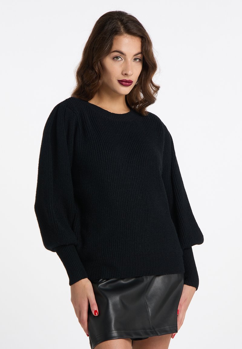 Maglione nero lavorato a maglia con scollatura rotonda e maniche a sbuffo, design testurizzato, abbinato a una gonna di pelle nera.
