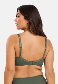 Reggiseno verde oliva con texture liscia, spalline in satin regolabili, chiusura posteriore con ganci e labbro scallopato lungo i bordi.