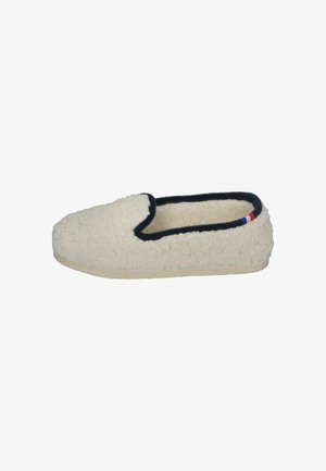 Cream-colored slipper made of soft, textured fabric with a black border, featuring a tricolor accent on the side. Flat sole for indoor use.