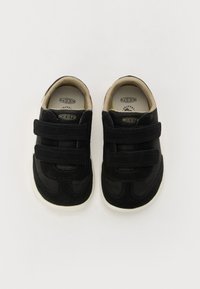 Sneakers neri per bambini con cinturini in velcro, materiale scamosciato, suola in gomma bianca, punta rotonda e fodera interna beige. Logo del marchio sulla linguetta.