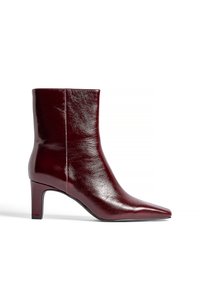Bottine en cuir bordeaux avec un bout pointu, texture lisse et un talon de 6,5 cm. Présente un design épuré et minimaliste.