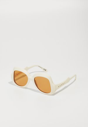 Lunettes de soleil en plastique blanc avec des montures carrées, verres teintés orange et un détail de logo subtil sur la branche. Texture lisse, design moderne.