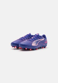 Zapatillas deportivas en púrpura con acentos en rosa, que cuentan con un diseño elegante, una superficie texturizada y una suela multigrosor para mayor tracción.