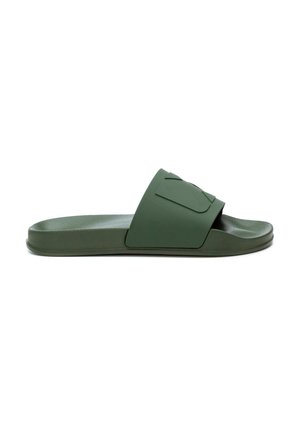 Sandalia de goma verde con suela plana y una amplia correa superior que presenta un diseño geométrico elevado. Textura suave, estilo minimalista.