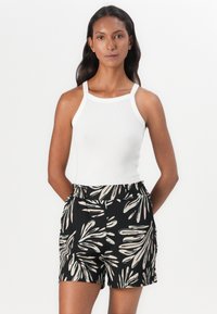 Débardeur blanc à côtes avec des bretelles fines, associé à un short noir orné d'un motif de feuillage clair et d'une taille élastique.