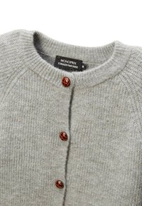 Cardigan en tricot gris avec un col rond, cinq boutons en plastique marron et une finition texturée en laine. Étiquette visible à l'intérieur.