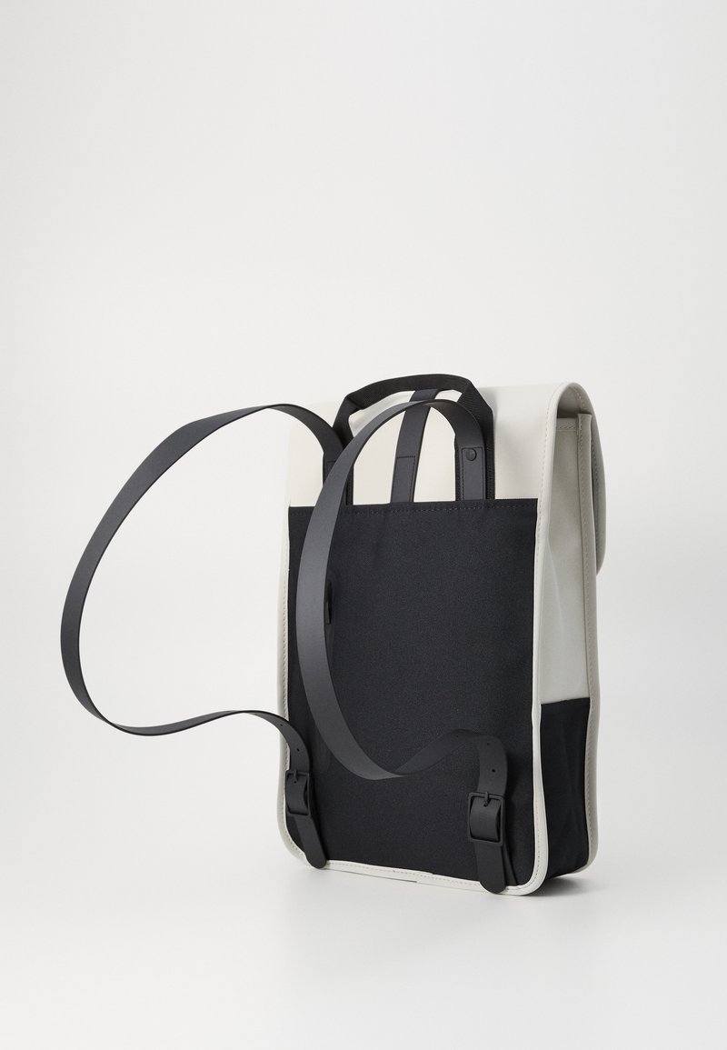 Sac à dos noir et blanc au design épuré, fabriqué en tissu et en matériau synthétique, avec des sangles réglables et des boucles latérales.