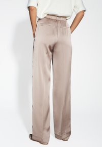 Lichtbeige satijnen broek met een relaxte pasvorm, elastische tailleband en twee achterzakken. Gladde textuur met een subtiele glans.