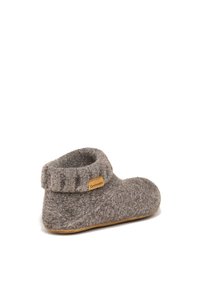 Pantofole in feltro di colore marrone chiaro, con un polsino a coste e una piccola etichetta. Forma arrotondata con suola piatta per l'utilizzo indoor.