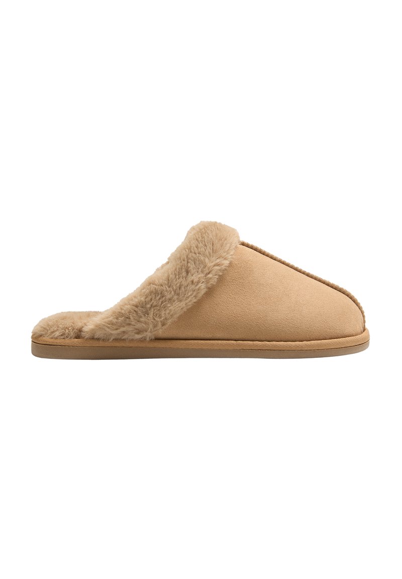 Zapatilla beige hecha de suave ante, con un acogedor borde de piel de peluche en la parte superior, diseño de fácil colocación y suela de goma flexible.