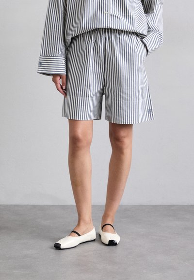 Shorts en coton à rayures avec taille élastique ; accompagnés de ballerines blanches avec un embout noir et une bride. Design simple et fonctionnel.
