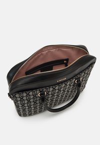 Sac à main en tissu noir et gris avec motif de logo, fermeture éclair dorée et dessus en cuir lisse. L'intérieur présente une doublure rose et une poche supplémentaire.