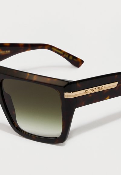 Gafas de sol de carey con montura cuadrada, lentes verde degradado y un acento dorado en la patilla con grabado de la marca.