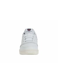 White leather sneakers with a textured rubber sole, lace closure, and a logo tag at the tongue featuring red and blue accents.