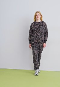 Melnas krūšturis un bikses komplekts ar rozā leoparda rakstu. Izgatavots no mīksta auduma, ar brīvu piegriezumu un elastīgām aprocēm.