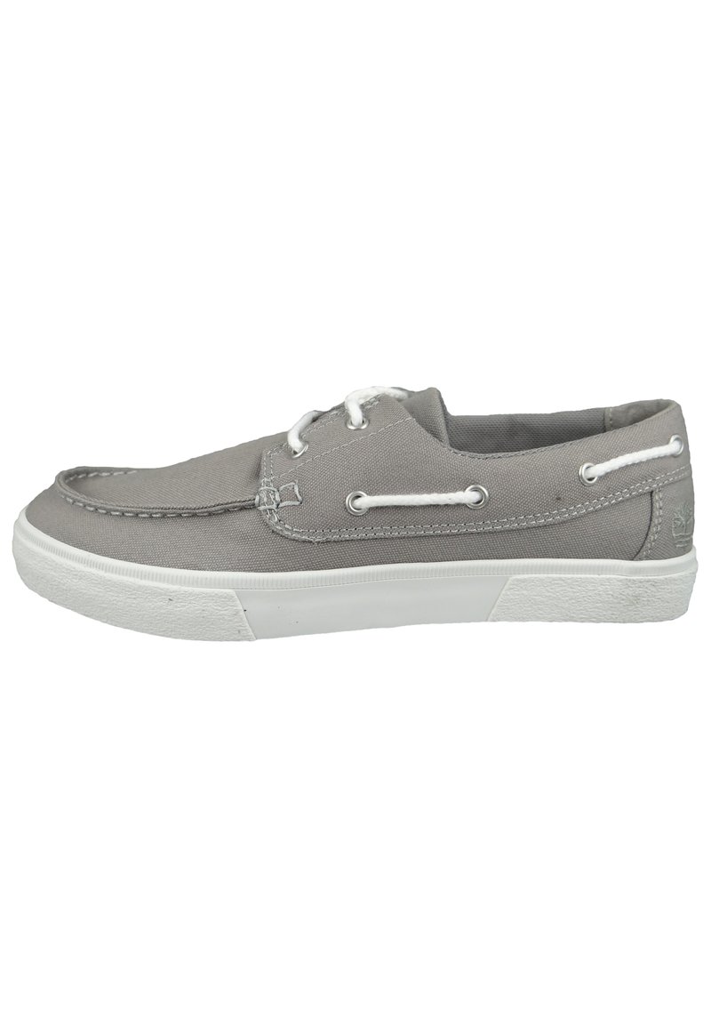 Zapato de lona gris con suela de goma blanca, diseño de cordones, detalles cosidos y ojales de metal para los cordones.