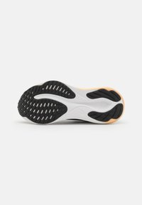 Zwart-witte sportschoen zool met een getextureerd rubberen grip patroon, een soepele tussenzool overgang en lichtoranje accenten.