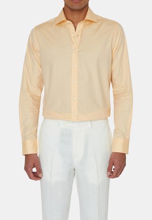 Lichtoranje langarmshirt met een puntige kraag, gladde textuur en witte knopen, gecombineerd met witte linnen broek.