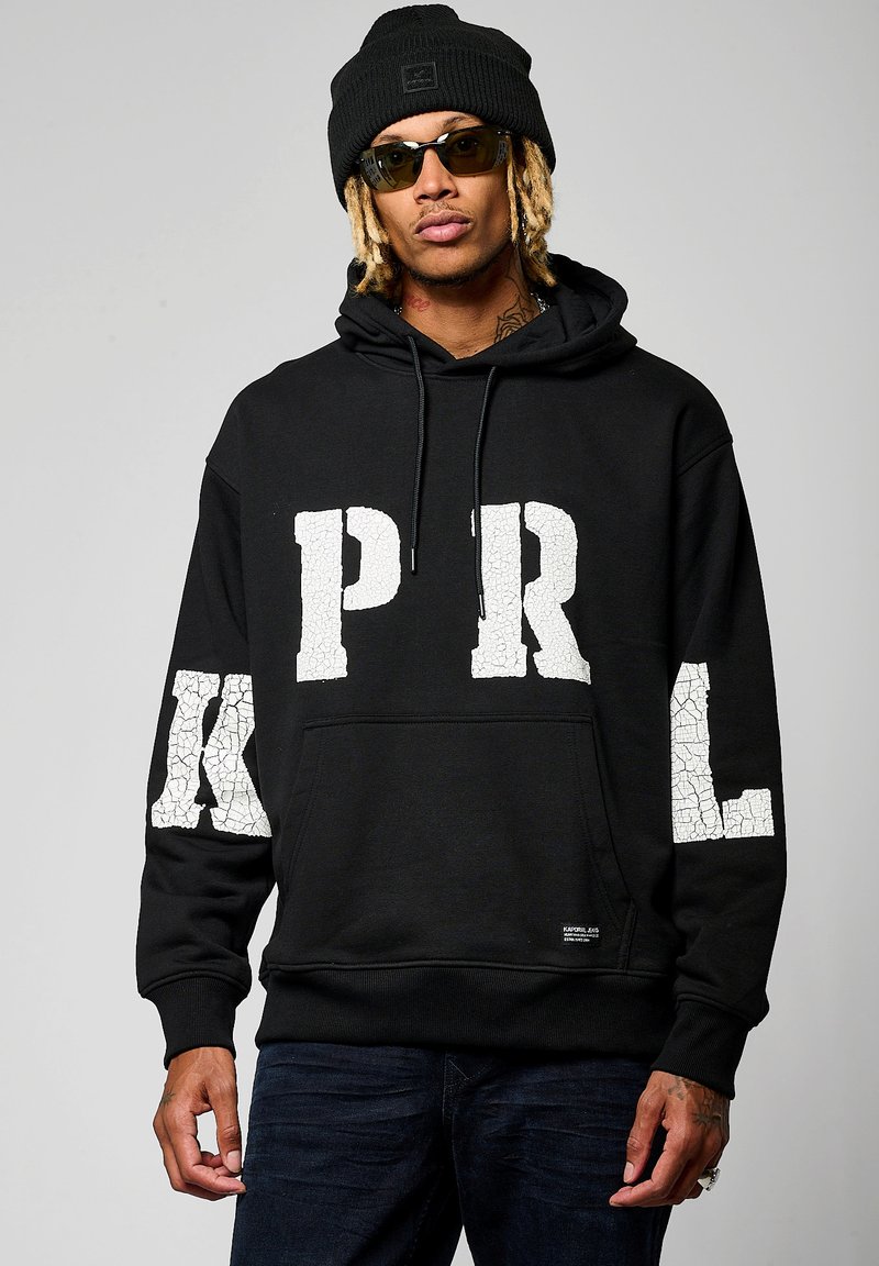 Hoodie noir en coton, décoré de grandes lettres blanches craquelées "PRL" sur le devant et les manches. Comprend une poche avant et une capuche.