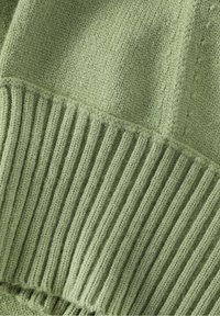 Strickpullover in Hellgrün mit strukturiertem, geripptem Saum. Der Stoff wirkt weich und weist sichtbare Nähdetails auf.