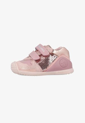 Zapatilla deportiva rosa con acentos metálicos y paneles laterales de lentejuelas. Cuenta con correas de Velcro y una suela de goma texturizada para mayor agarre.