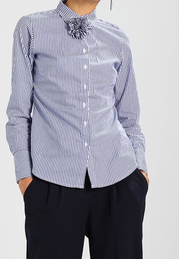 Blue and white striped button-up shirt with long sleeves and a high collar adorned with a fabric flower detail at the neck.