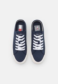 Marina canvas sneakers med vita snören, texturerad ovandel, gummisulor och en Tommy Jeans-logotyp på tungan samt QR-kod inuti.