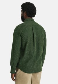 Groene longsleeve shirt van een gestructureerde stof, met een rugplooidetail en knoopmanchetten, voorzien van een subtiele gestructureerde print.