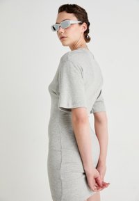 Szürke, rövid ujjú ruha testhez simító szabásban. A modellen szürke, téglalap alakú napszemüveg van. Sima, puha tapintású anyag.