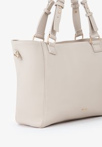 Borsa a mano in pelle beige con finitura testurizzata, doppi manici regolabili, dettagli in metallo dorato e forma rettangolare strutturata.
