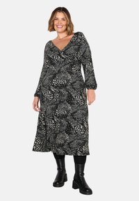 Abito a righe in bianco e nero con design avvolgente, maniche lunghe e orlo a metà gamba, abbinato a stivali neri al ginocchio.