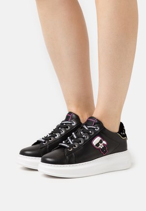 Czarne skórzane sneakersy z białą podeszwą, z grafiką postaci, kolorowymi sznurówkami i ćwiekowanymi akcentami na pięcie.