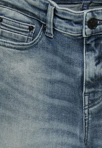 Gaiši zilas džinsa bikses ar izbalējušu apdari, aprīkotas ar pogu un rāvējslēdzēja aizdari, priekšējām un aizmugurējām kabatām, kā arī kontrastējošām šuvēm.