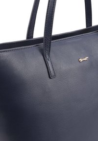 Marine lederen schoudertas met twee handvaten, zachte textuur en een klein gouden konijnenembleem aan de voorkant. Eenvoudig, gestructureerd ontwerp.