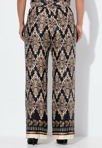 Zwart en goud patroon wijdebroek met een elastische tailleband, versierd met verfijnde motieven en een contrasterende zoomdetail. Gladde textuur.