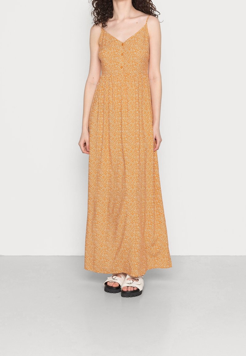 Robe longue orange à motif floral, avec un col en V, des bretelles fines et des détails boutonnés ; longueur au sol avec une silhouette fluide et ample.