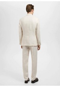 Costum din in de culoare bej deschis, cu un sacou structurat și pantaloni drepti, având hardware minim și o textură lipsită de cusur.
