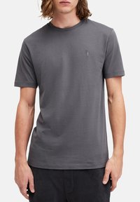 T-shirt grigio a manica corta in tessuto morbido con scollatura rotonda. Presenta un piccolo logo discreto sul petto sinistro. Design semplice e minimalista.