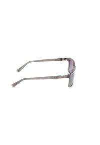 Gafas de sol grises con un diseño elegante, que cuentan con un marco curvado, lentes ahumados y patas de plástico resistentes con un sutil detalle de marca.