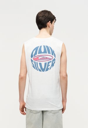 Mlad moški, obrnjeni stran, oblečen v belo majico brez rokavov z velikim modro-rdečim logotipom Quiksilver na hrbtu.